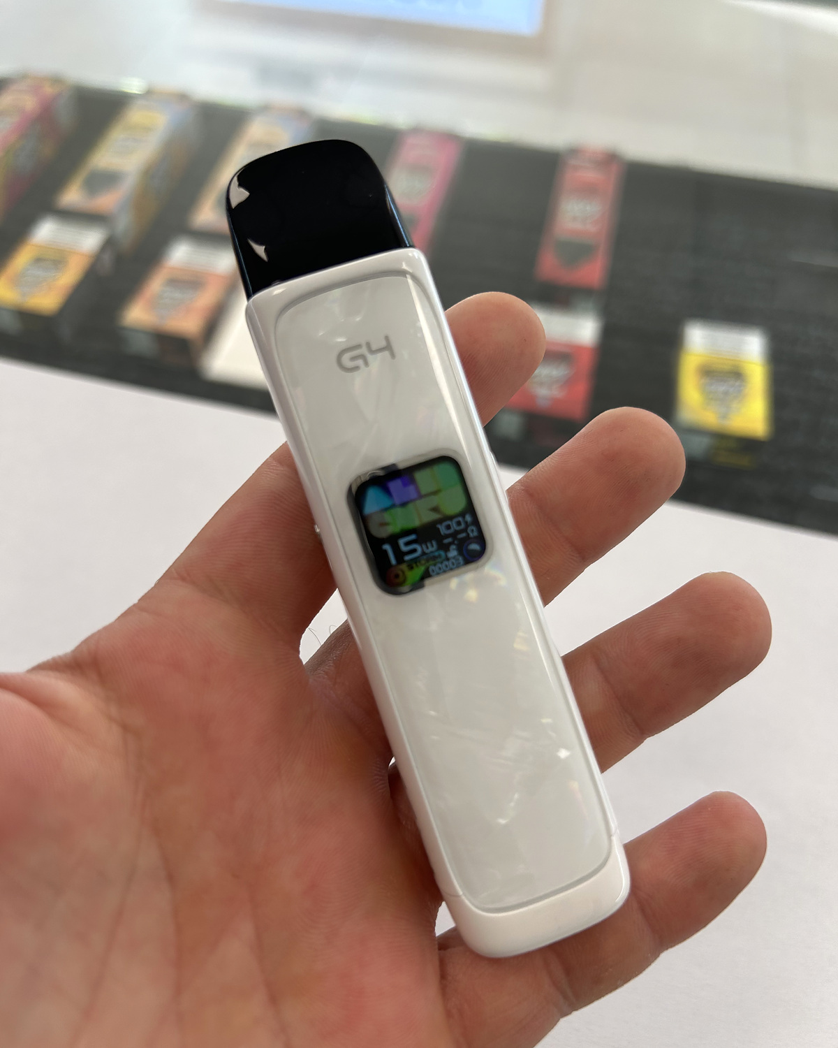 Bílý Uwell Caliburn G4 s černou cartridge v ruce