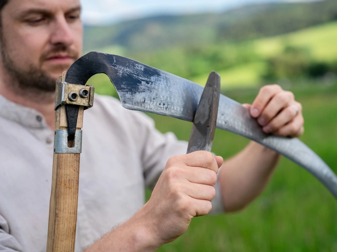 Honing a scythe with a whetstone