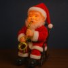 Santa Claus so saxofónom na hojdacom kresle – svieti, hýbe sa a hrá hudbu (23 cm)
