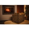 Vingo velký šedý úložný ratanový koš s dlouhými poleny stojící u krbu ve večerních hodinách.
