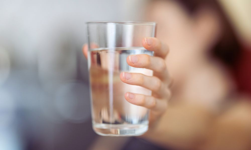 Ako sa zbaviť dusičnanov vo vode – Pohár čistej vody v ruke, symbolizuje filtrovanú pitnú vodu.