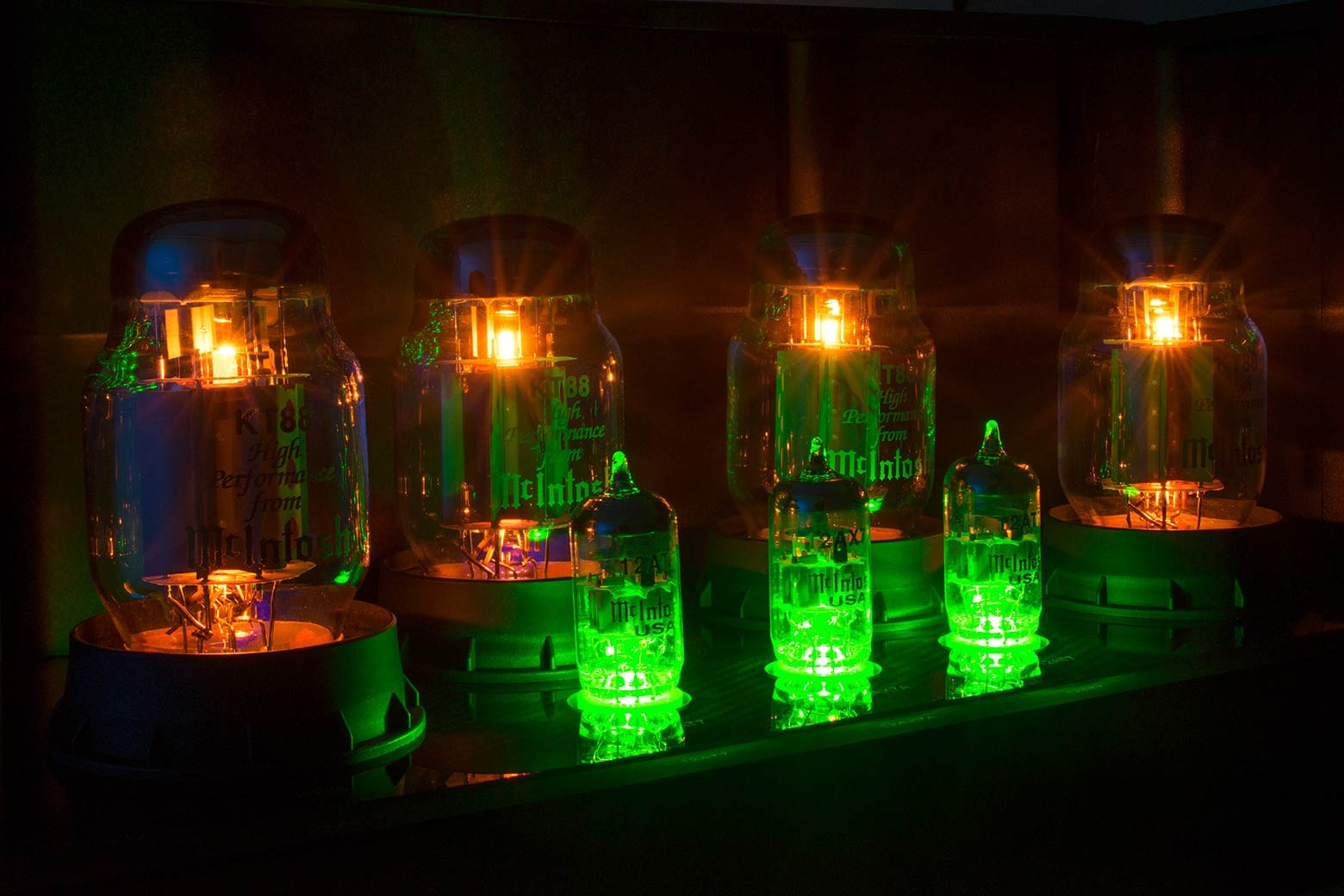 Detail žhnoucích výstupních elektronek KT88 a menších signálních elektronek McIntosh MC901 se zeleným podsvícením