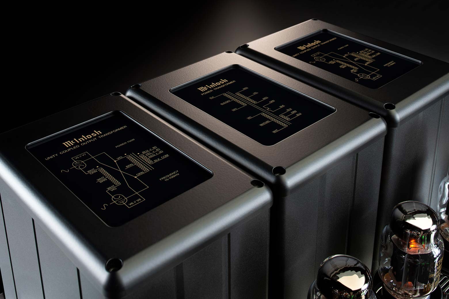 Tři skleněnými deskami kryté transformátory McIntosh MC1502 se zlatě tištěnými schématy zapojení