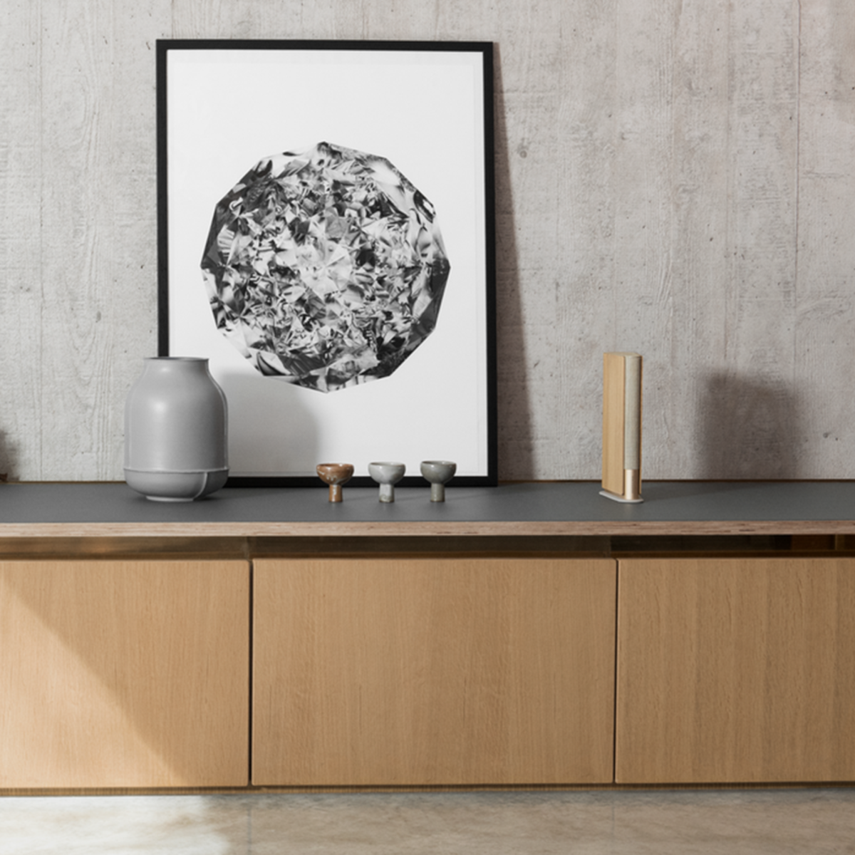 Beosound Emerge v dubovém provedení v minimalistickém japandi interiéru s betonovou stěnou a komodou