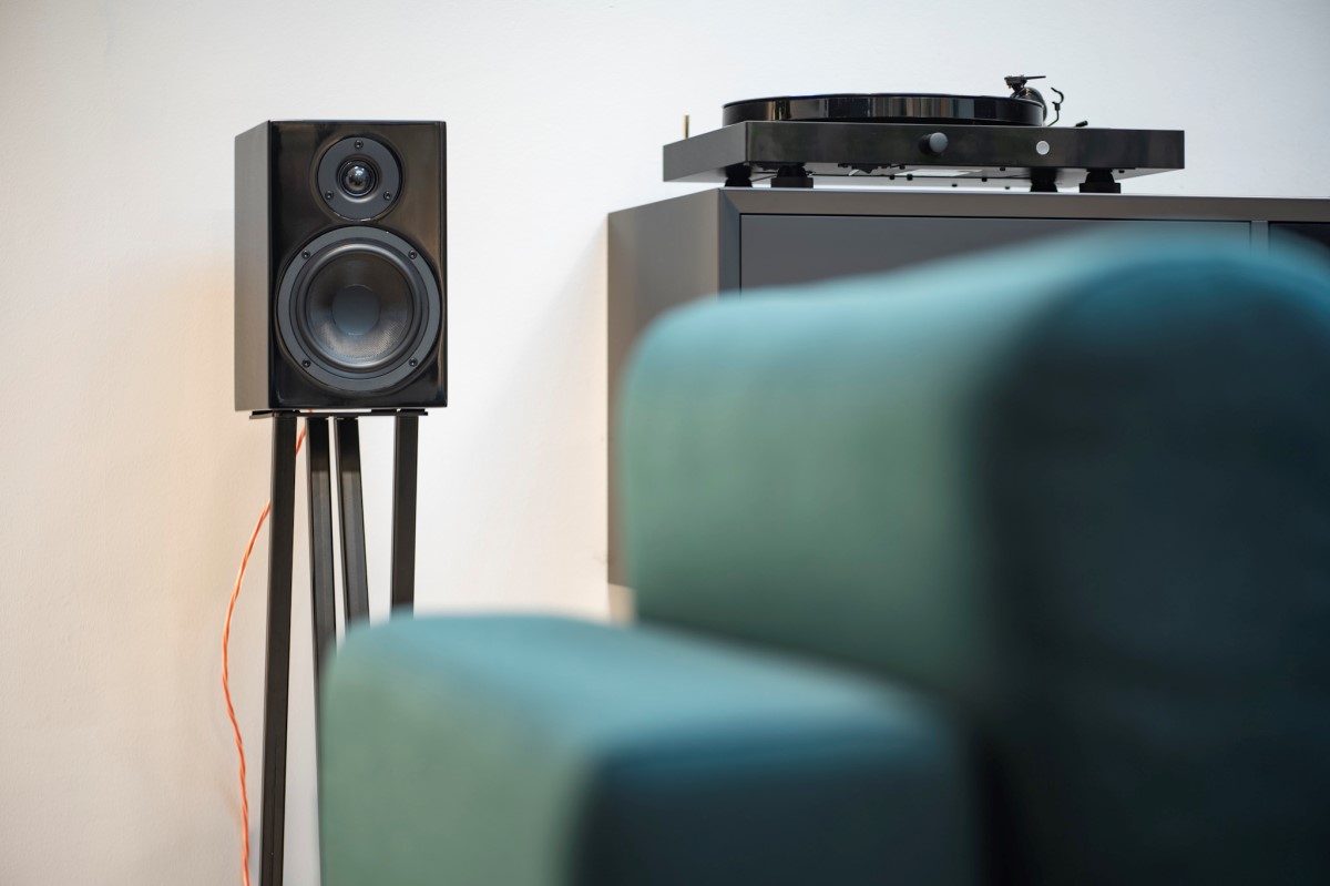 Pro-Ject JukeBox E1 HiFi Set v černém provedení na nástěnné konzoli, reproduktory na stojanech a sbírka vinylových desek
