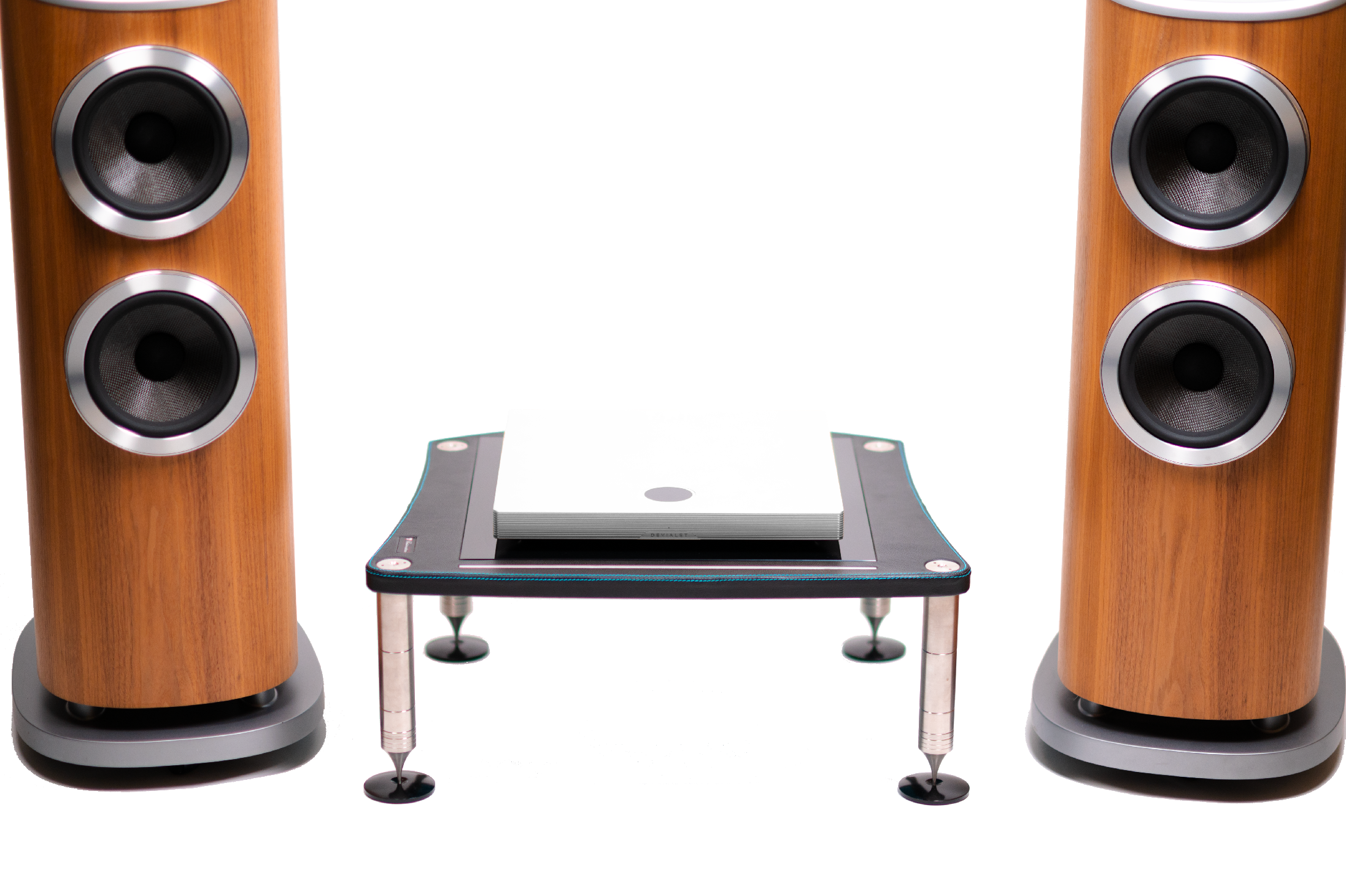 Spodní část sestavy — basové měniče Aerofoil obou věží Bowers & Wilkins 803 D4 ve světlém dřevě, mezi nimi zesilovač Devialet Astra na nízkém skleněném stolku s hroty