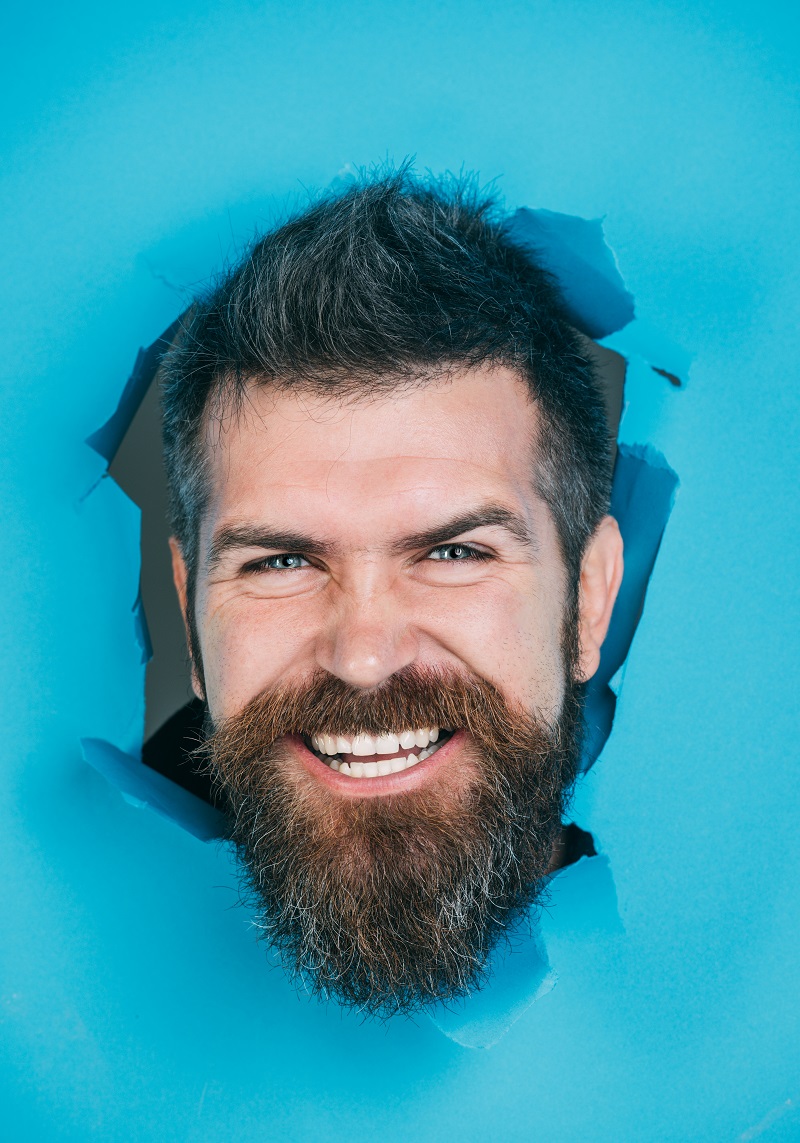 bearded-man-looking-through-blue-paper-view-male-face-through-paper-smiling-bearded-man-making