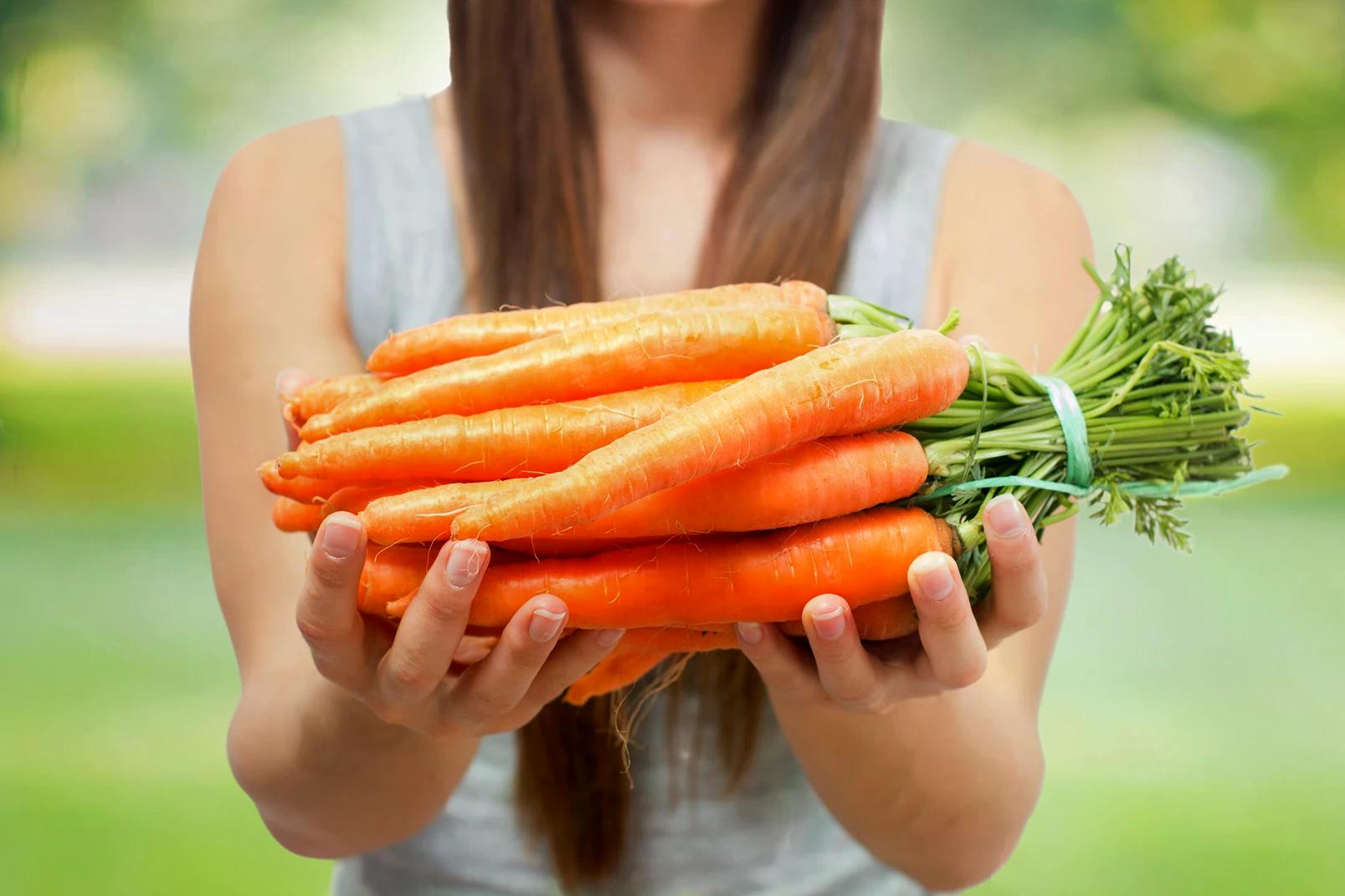 40338_woman-holds-fresh-carrots-in-outdoor-setting-2026-03-26-05-00-36-utc_11zon