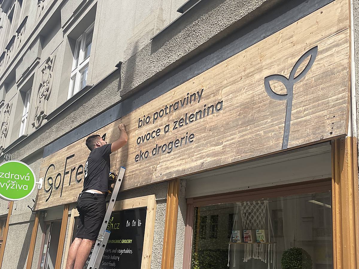 Původní vybledlý dřevěný obklad nad výlohou před demontáží