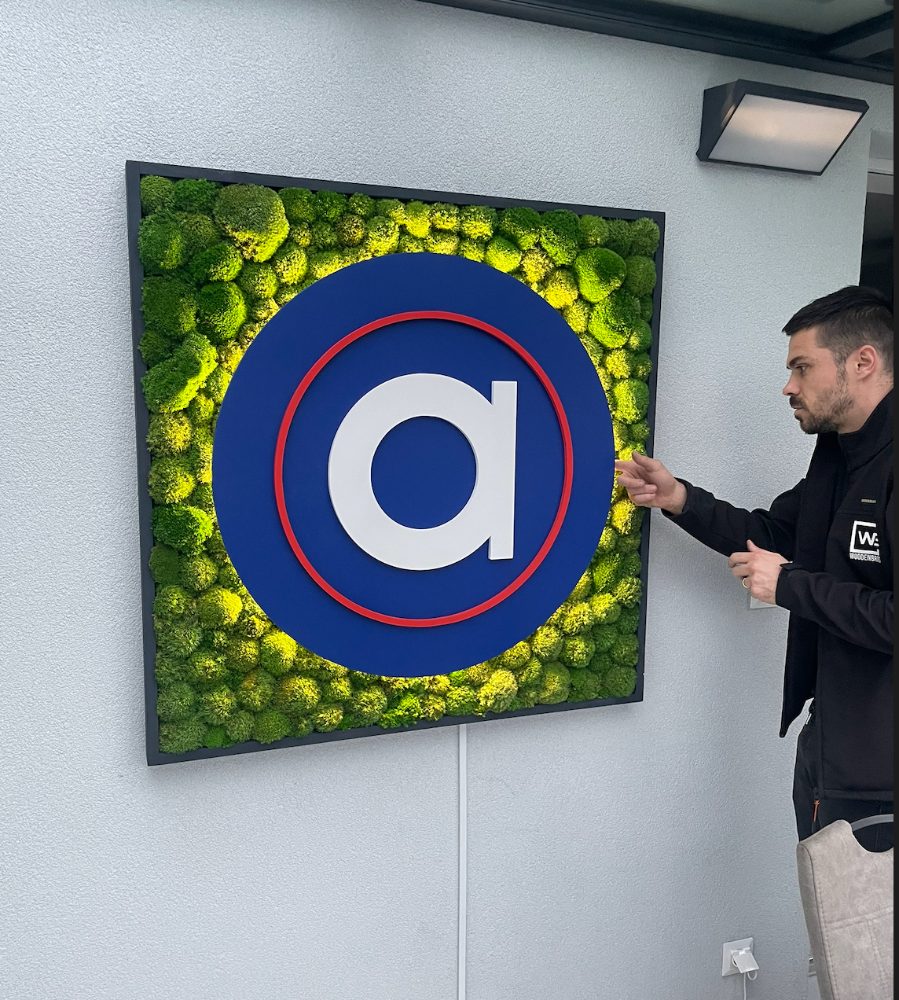 Mechový obraz s kulatým 3D logem na zdi