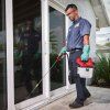 Dělník v rukavicích aplikuje postřik na rostliny s aku postřikovačem Milwaukee M12 BHCS3L.