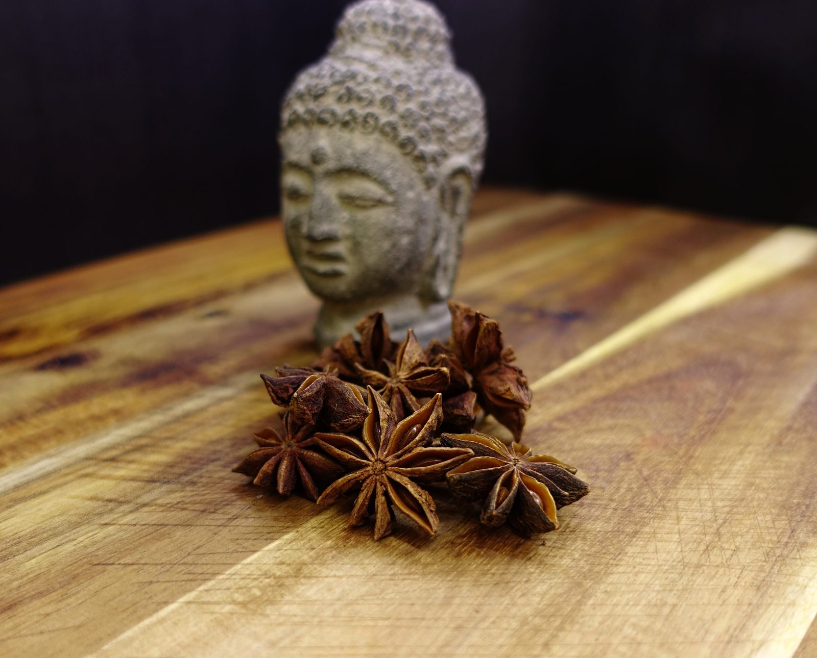 Hviezdičky badiánu na drevenej doske so soškou Budhu