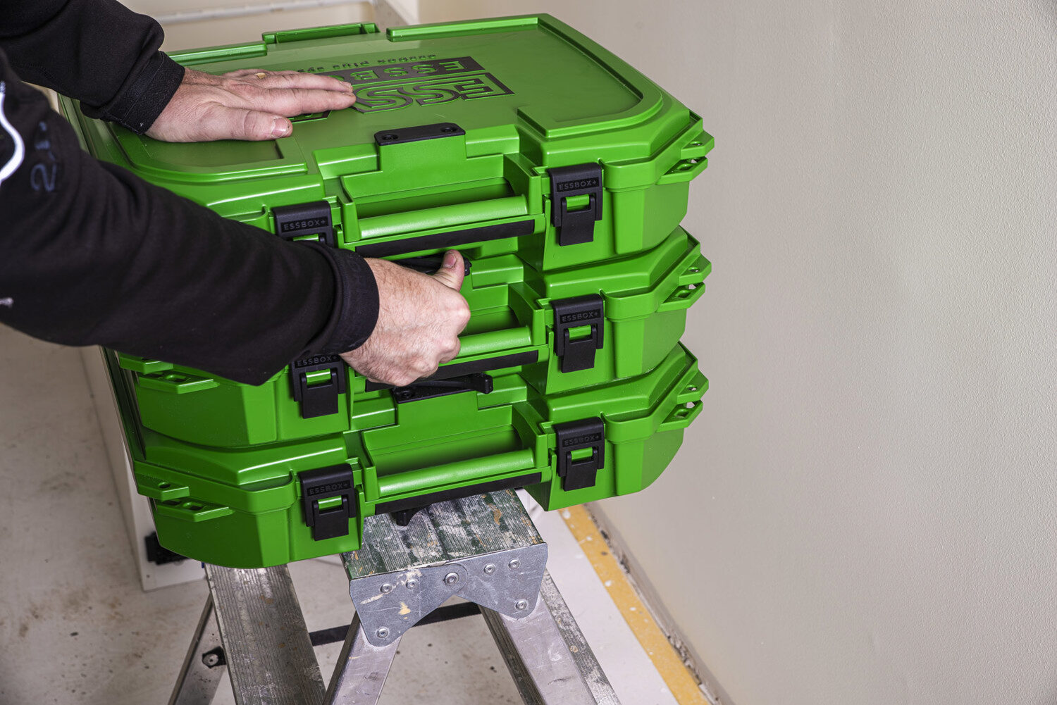 Tri spojené kufre ESSBOX+ stoja na rebríku.