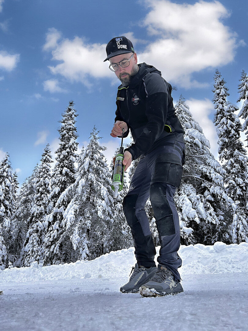Stolár v zasneženej krajine drží lepidlo ESSTACK Nordic Pro. 